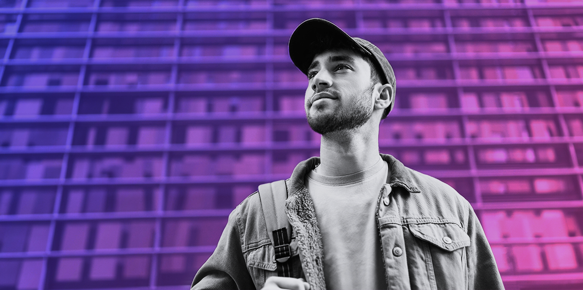 young man in a baseball cap looking up on a purple and pink gradient background