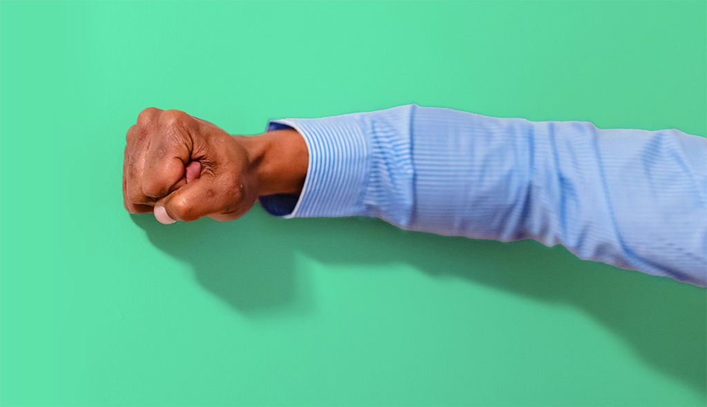 man's arm, fist clenched, against a bright green background.