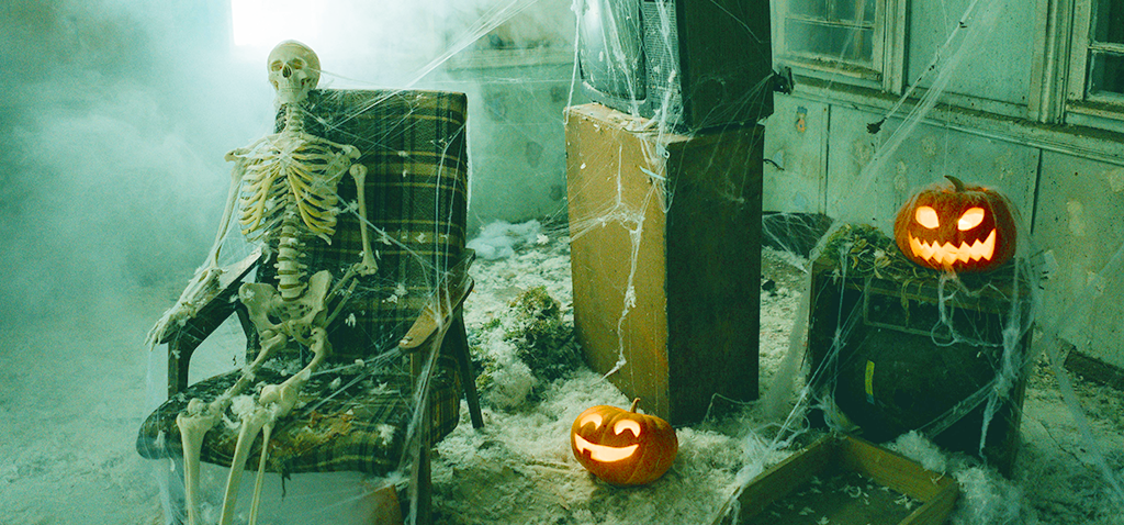Skeleton and 2 jack-o-lanterns in a spooky-looking room