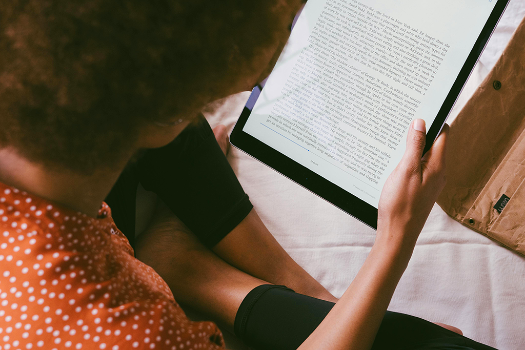 The view over the shoulder of a young woman reading an ebook on an ereader