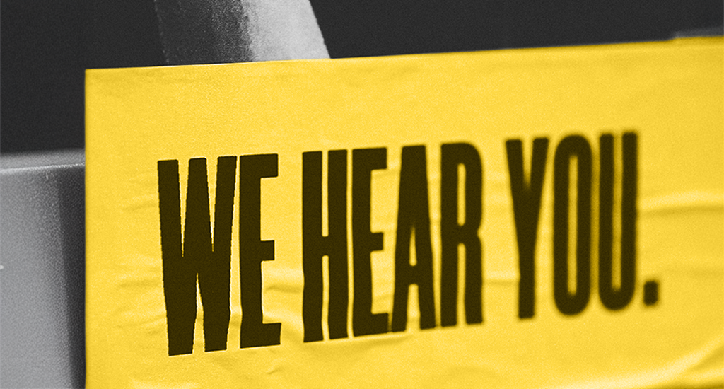 "WE HEAR YOU" on yellow paper