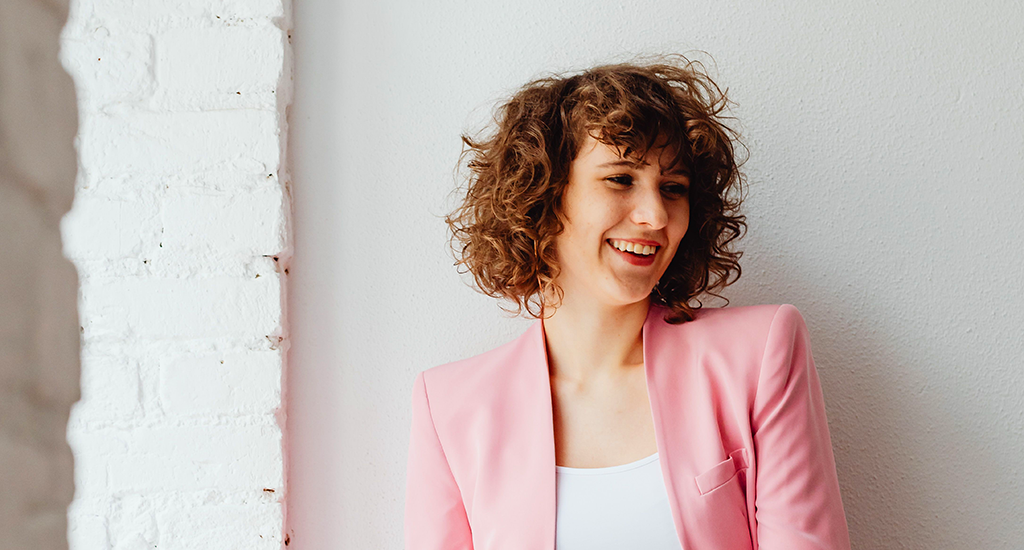 Young professional woman smiling in a pink suit jacket
