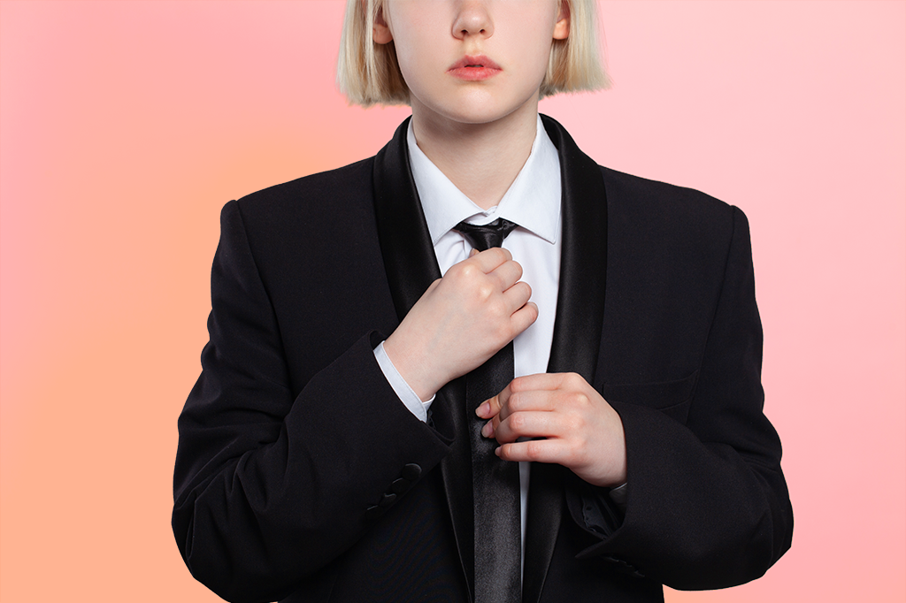 A partial view of a young woman in a suit jacket as she adjusts her tie.